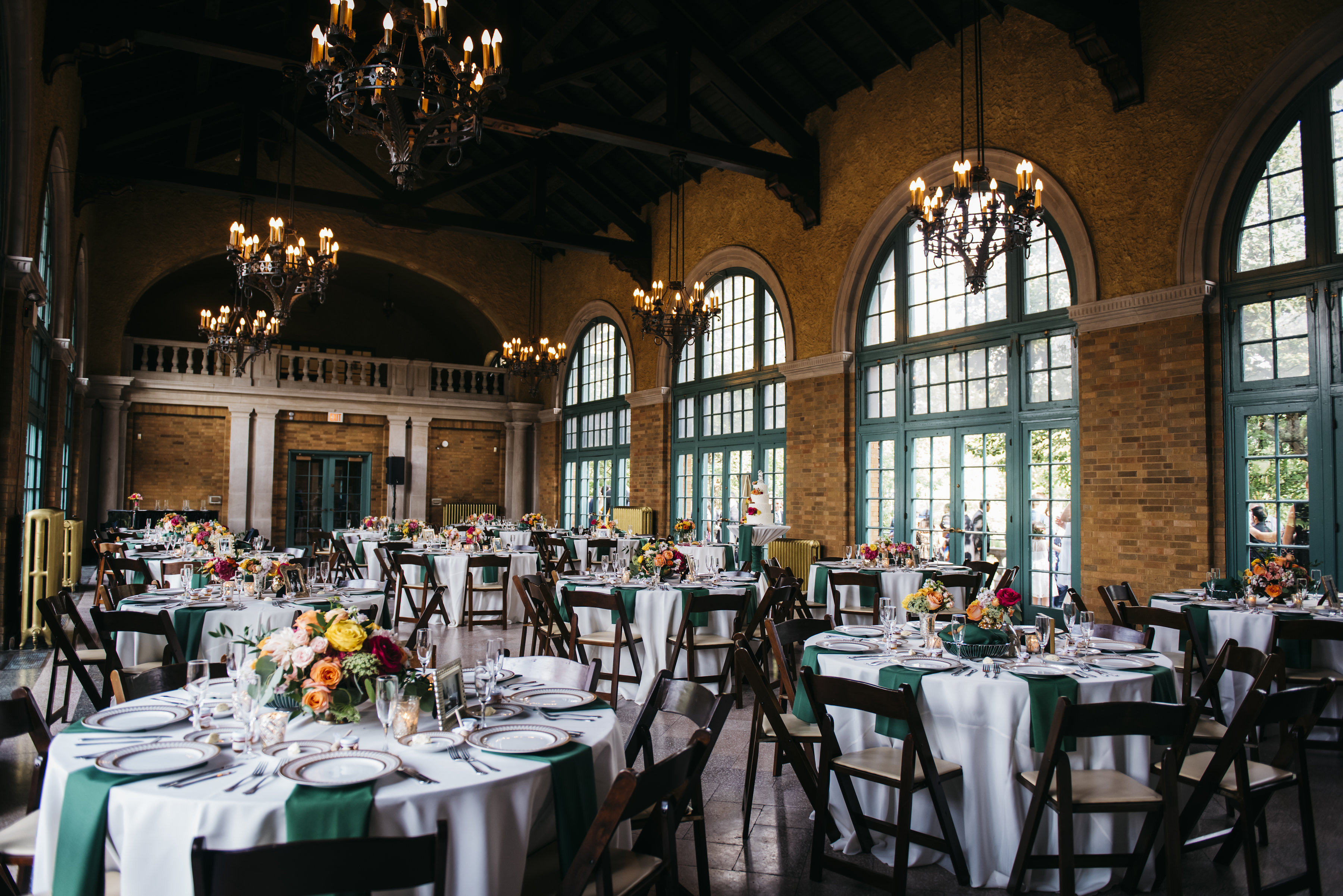 Elegant wedding reception hall with round tables, floral centerpieces, and chandeliers.